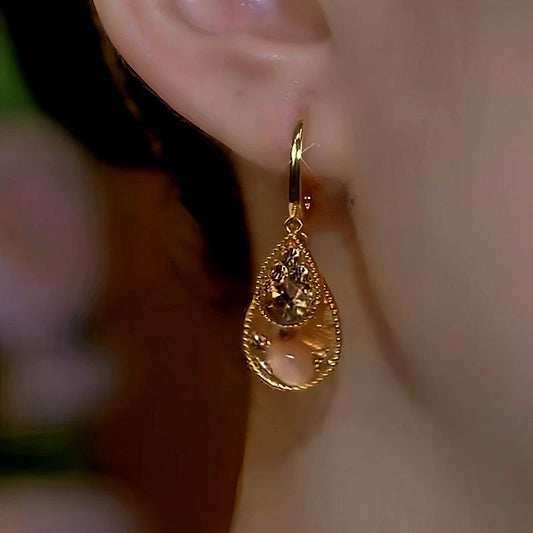 Model showcasing the dangle and style of the 14K Gold-Plated Brown Crystal Water Drop Earrings
