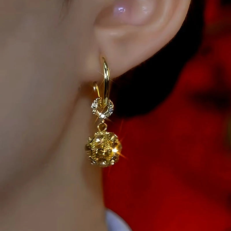 Model showcasing the dangle and style of the 14K Gold-Plated Brown Diamond Ball Earrings