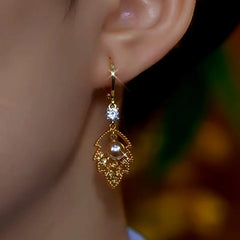 Model showcasing the dangle and style of the 14K Gold-Plated Brown Diamond Leaf Earrings
