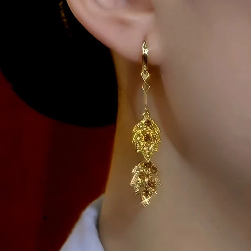 Model showcasing the dangle and style of the 14K Gold-Plated Brown Diamond Leaf Tassel Earrings