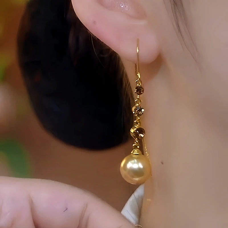 Model showcasing the dangle and style of the 14K Gold-Plated Brown Diamond Pearl Threader Earrings