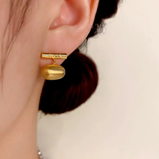 Model showcasing the dangle and style of the 14K Gold-Plated Brushed Bean Earrings