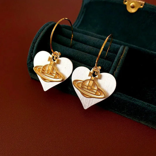 Model showcasing the dangle and style of the 14K Gold-Plated Brushed Heart Saturn Earrings