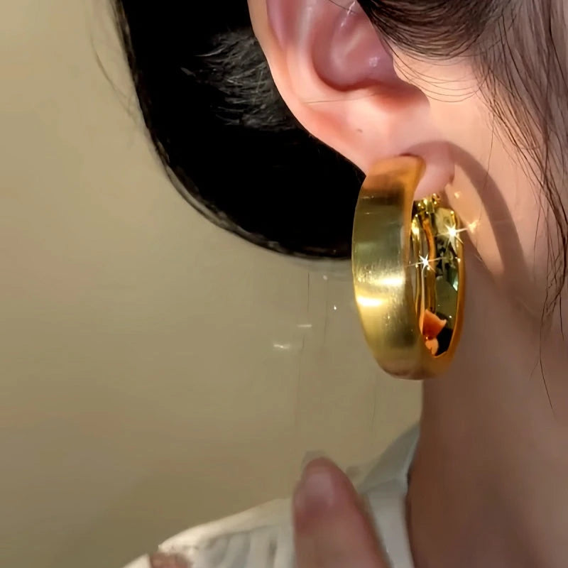 Model showcasing the dangle and style of the 14K Gold-Plated Brushed Hoop Earrings