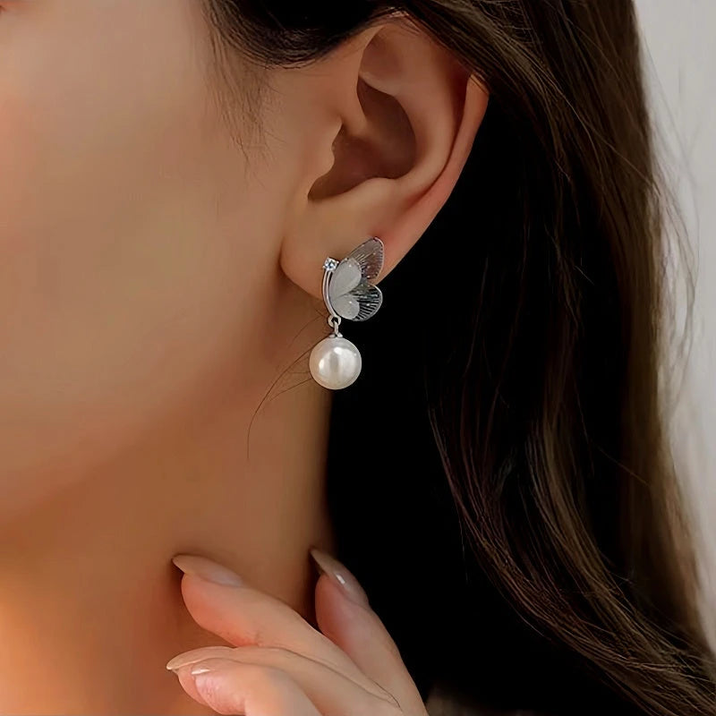 Model showcasing the dangle and style of the 14K Gold-Plated Butterfly Pearl Earrings