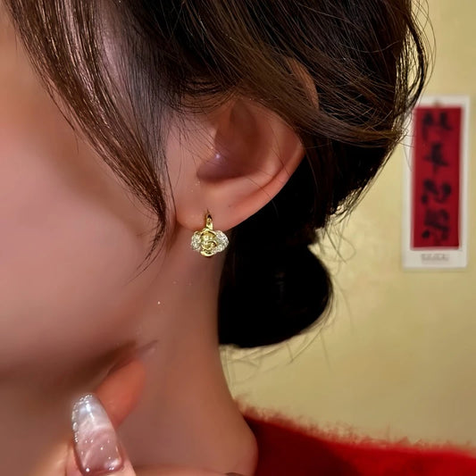Model showcasing the dangle and style of the 14K Gold-Plated Camellia Hoop Earrings