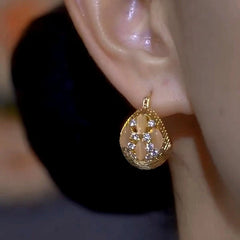 Model showcasing the dangle and style of the 14K Gold-Plated Cat's Eye Basket Ball Earrings