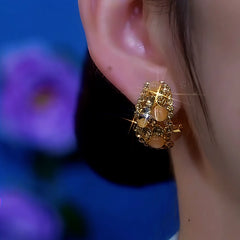 Model showcasing the dangle and style of the 14K Gold-Plated Cat's Eye Brown Diamond Earrings