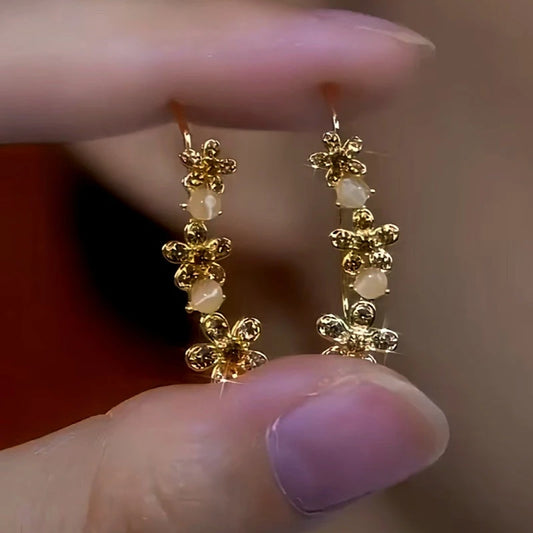Model showcasing the dangle and style of the 14K Gold-Plated Cat's Eye Brown Zircon Diamond Flower Crawler Earrings