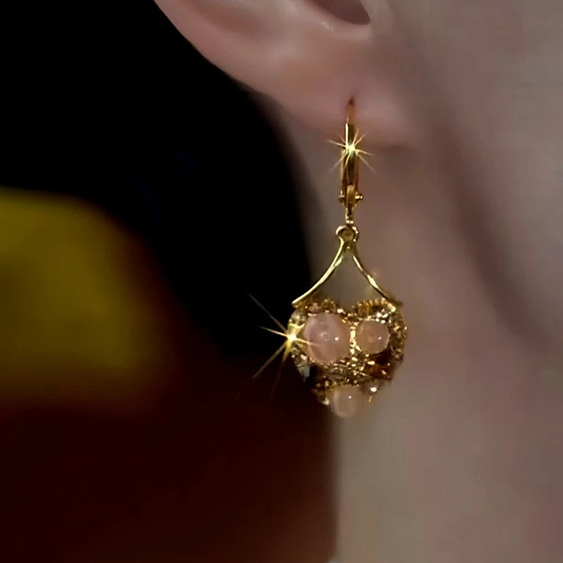 Model showcasing the dangle and style of the 14K Gold-Plated Cat's Eye Brown Zircon Diamond Heart Earrings