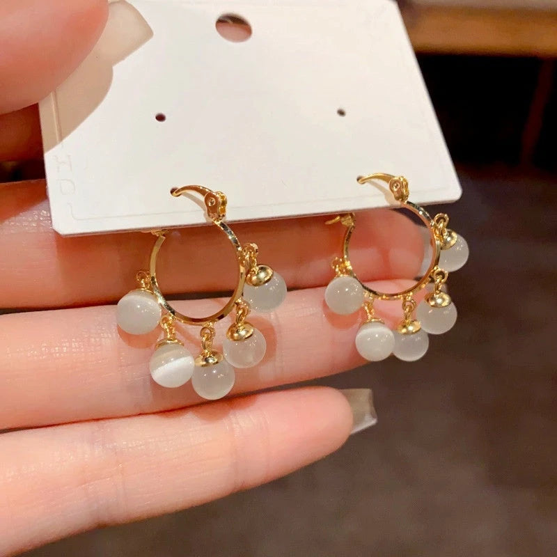 Model showcasing the dangle and style of the 14K Gold-Plated Cat's Eye Stone Ball Tassel Earrings