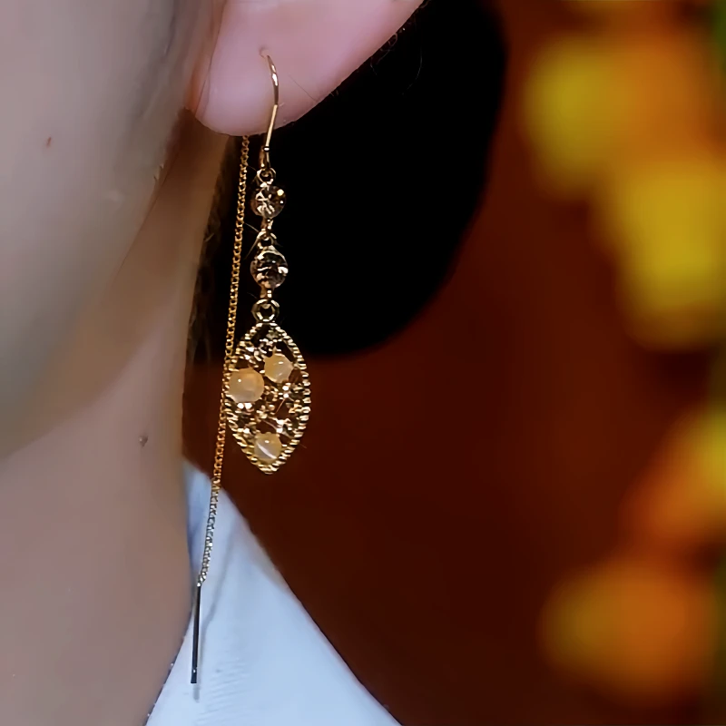 Model showcasing the dangle and style of the 14K Gold-Plated Cat's Eye Stone Brown Diamond Leaf Threader Earrings