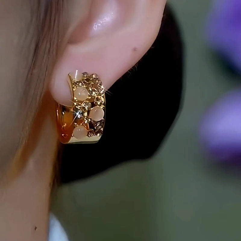 Model showcasing the dangle and style of the 14K Gold-Plated Cat's Eye Stone Brown Diamond Wide Hoop Earrings