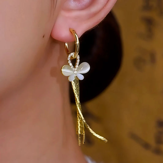 Model showcasing the dangle and style of the 14K Gold-Plated Cat's Eye Stone Butterfly Tassel Earrings