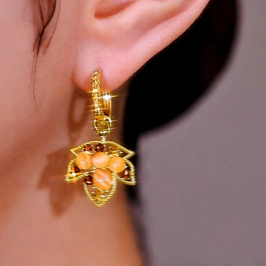 Model showcasing the dangle and style of the 14K Gold-Plated Cat's Eye Stone Diamond Maple Leaf Earrings