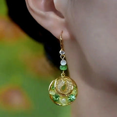 Model showcasing the dangle and style of the 14K Gold-Plated Cat's Eye Stone Green Diamond Mesh Water Drop Ear Hook Earrings