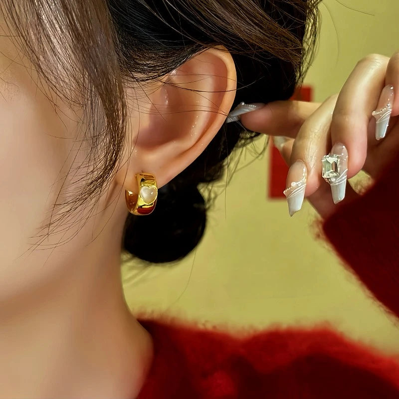 Model showcasing the dangle and style of the 14K Gold-Plated Cat's Eye Stone Hoop Earrings