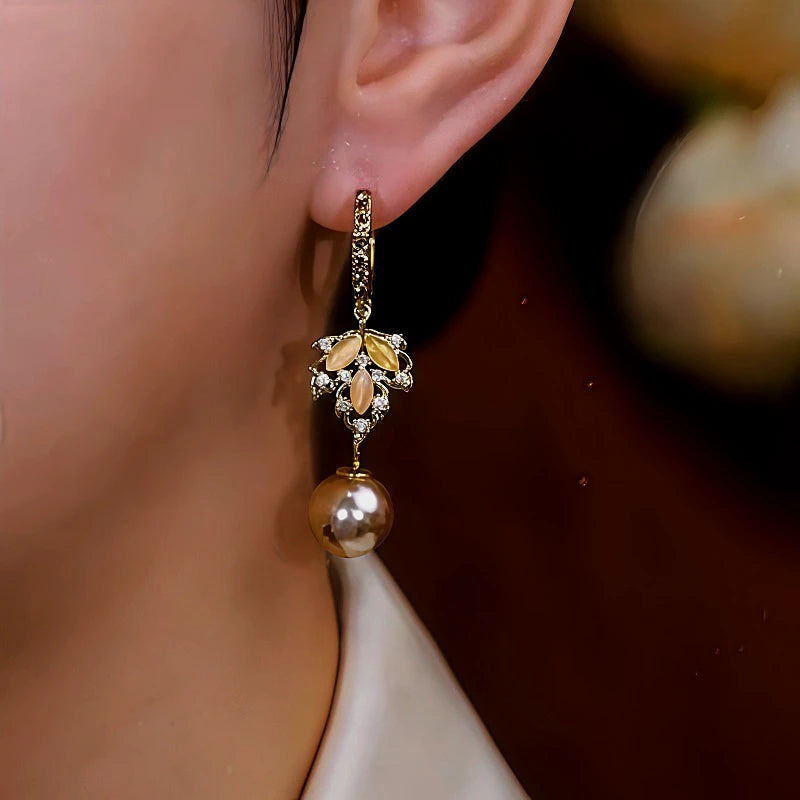 Angled view of the 14K Gold-Plated Cat's Eye Stone Maple Leaf Pearl Earrings