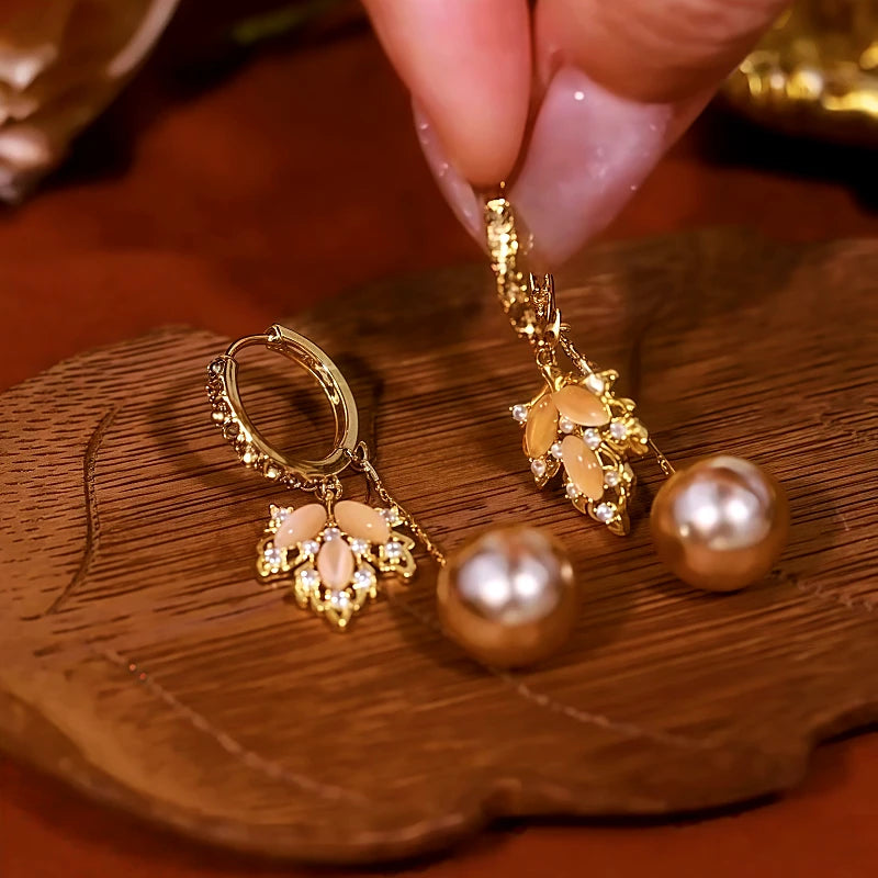 Model showcasing the dangle and style of the 14K Gold-Plated Cat's Eye Stone Maple Leaf Pearl Earrings