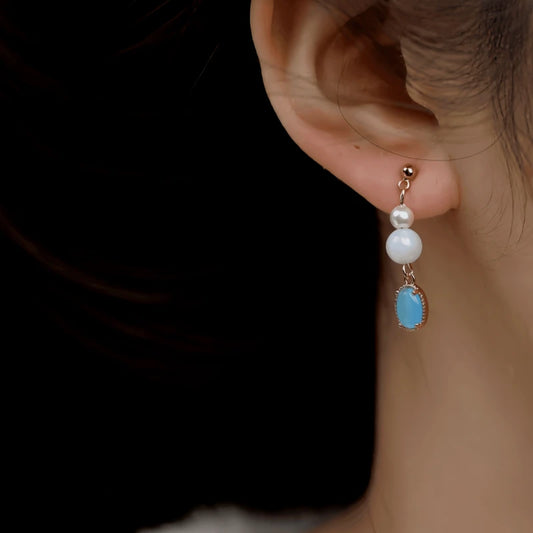 Model showcasing the dangle and style of the 14K Gold-Plated Cat's Eye Stone Pearl Bead Earrings