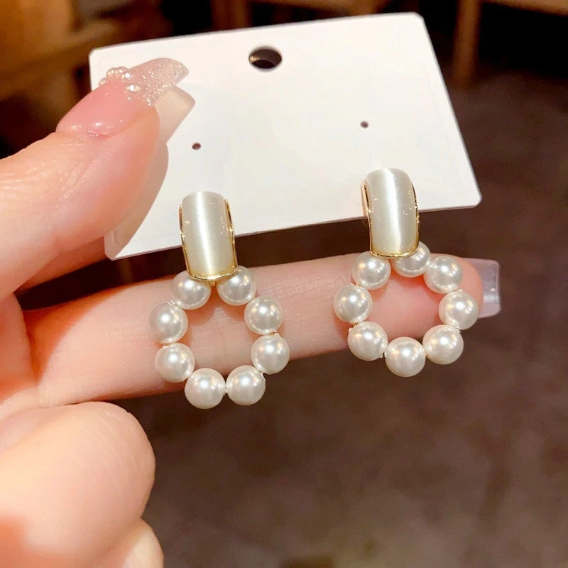 Model showcasing the dangle and style of the 14K Gold-Plated Cat's Eye Stone Pearl Swinging Earrings