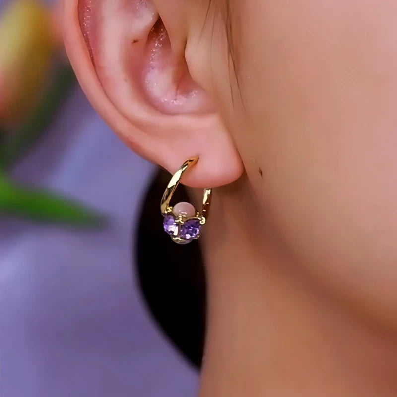 Model showcasing the dangle and style of the 14K Gold-Plated Cat's Eye Stone Purple Diamond Earrings