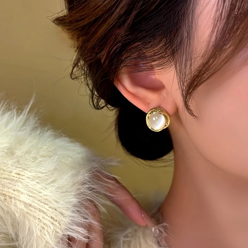 Model showcasing the dangle and style of the 14K Gold-Plated Cat's Eye Stone Stud Earrings