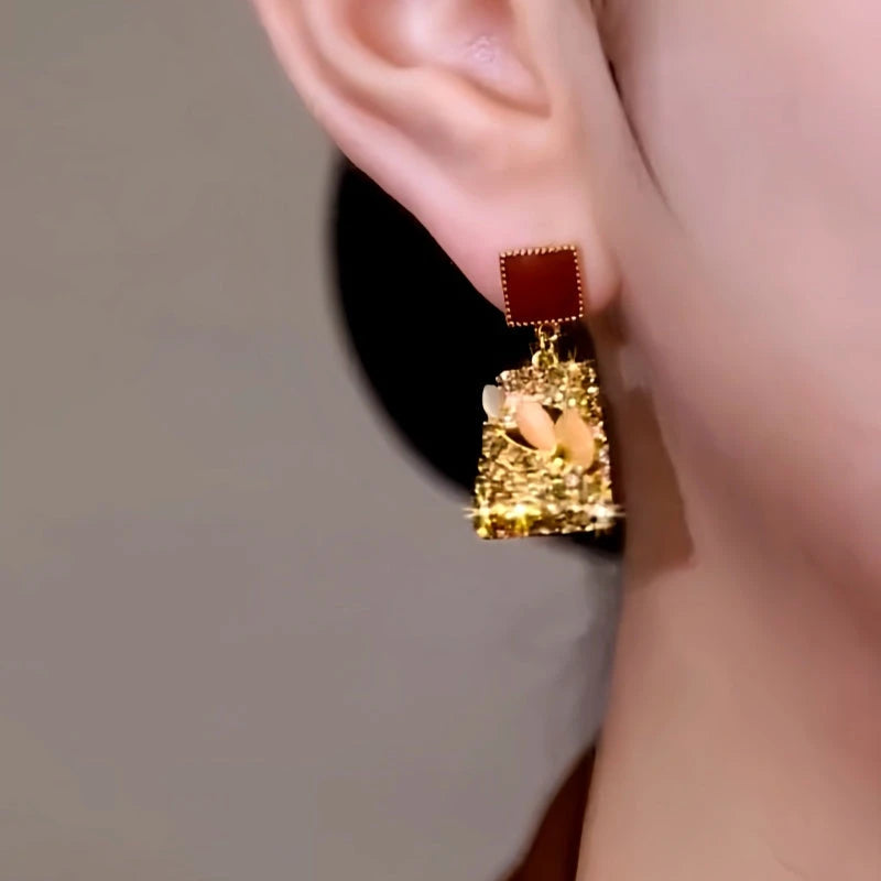 Model showcasing the dangle and style of the 14K Gold-Plated Cat's Eye Stone Zircon Diamond Cube Earrings