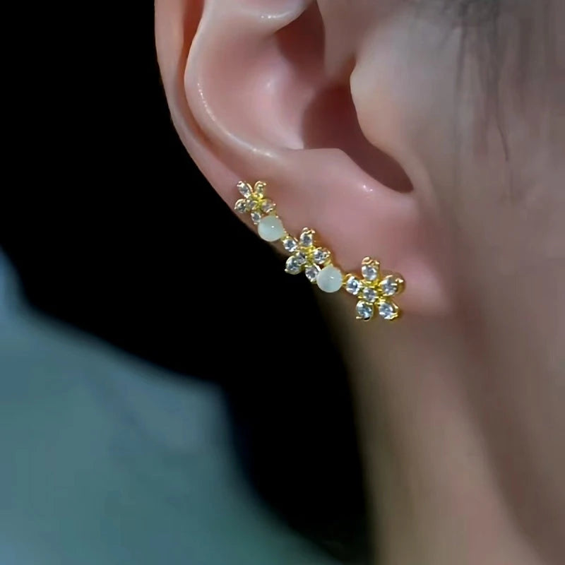 Model showcasing the dangle and style of the 14K Gold-Plated Cat's Eye Stone Zircon Flower Crawler Earrings