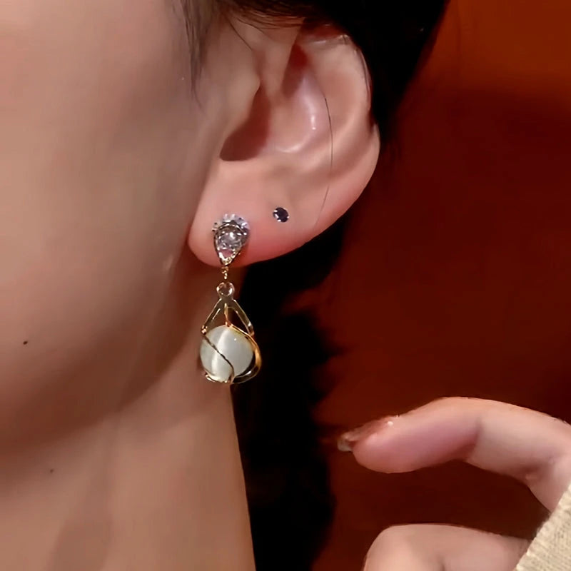 Model showcasing the dangle and style of the 14K Gold-Plated Cat's Eye Zircon Earrings