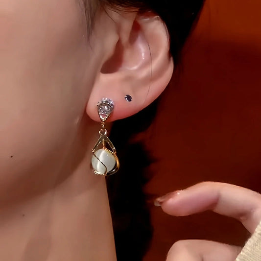 Model showcasing the dangle and style of the 14K Gold-Plated Cat's Eye Zircon Earrings