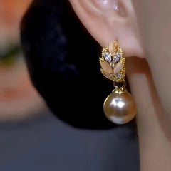 Model showcasing the dangle and style of the 14K Gold-Plated Champagne Cat's Eye Stone Wheat Ear Pearl Earrings