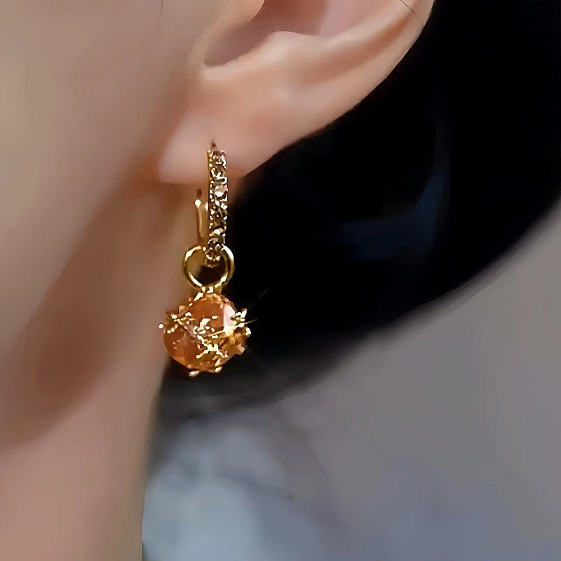 Model showcasing the dangle and style of the 14K Gold-Plated Champagne Diamond Ball Earrings