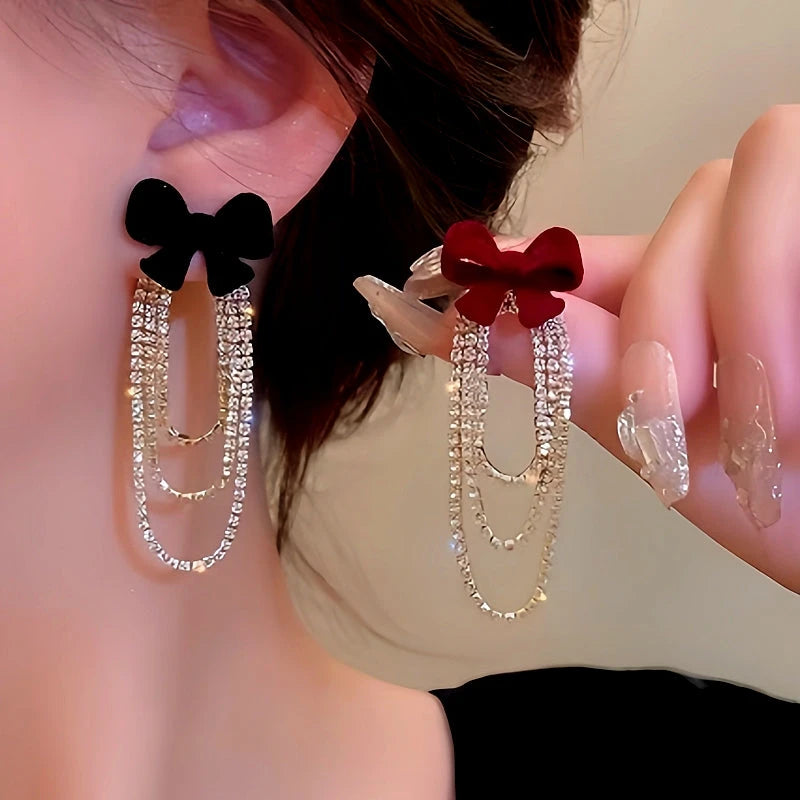 Model showcasing the dangle and style of the 14K Gold-Plated Christmas Diamond And Zircon Flocked Bow Tassel Earrings