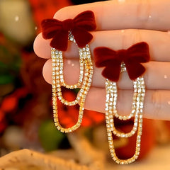 Angled view of the 14K Gold-Plated Christmas Diamond And Zircon Flocked Bow Tassel Earrings