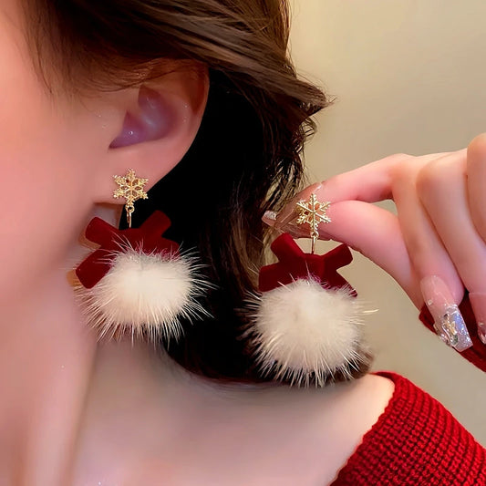 Model showcasing the dangle and style of the 14K Gold-Plated Christmas Fluffy Bow Earrings