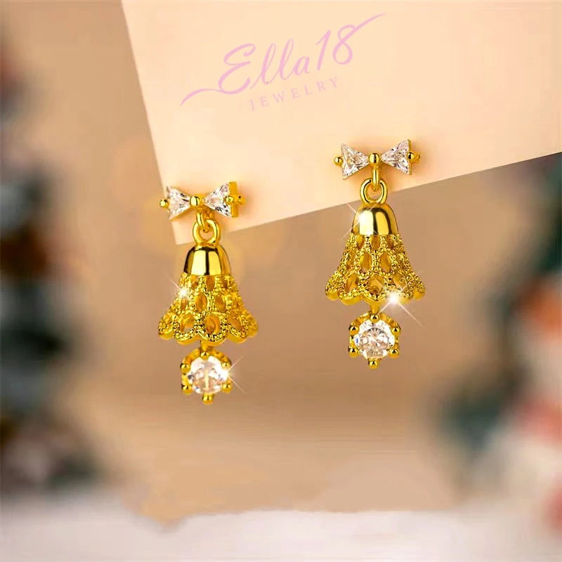 Model showcasing the dangle and style of the 14K Gold-Plated Christmas Tree Bow Bell Necklace And Earrings Set