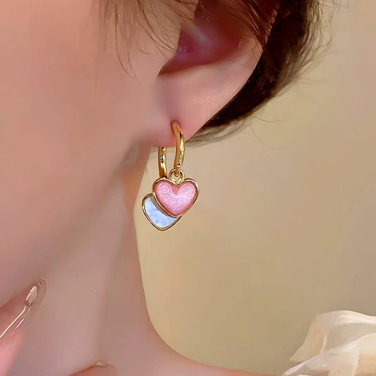 Model showcasing the dangle and style of the 14K Gold-Plated Contrasting Heart Earrings
