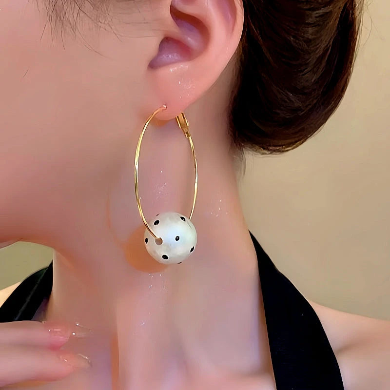 Model showcasing the dangle and style of the 14K Gold-Plated Cotton Pearl Ball Hoop Earrings