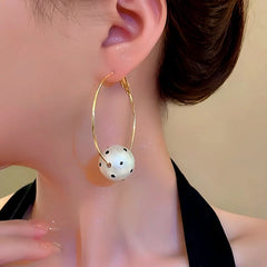Model showcasing the dangle and style of the 14K Gold-Plated Cotton Pearl Ball Hoop Earrings