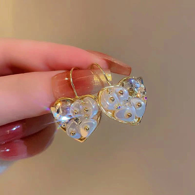 Model showcasing the dangle and style of the 14K Gold-Plated Crystal Heart-Design Earrings