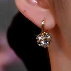Model showcasing the dangle and style of the 14K Gold-Plated Diamond Ball Earrings
