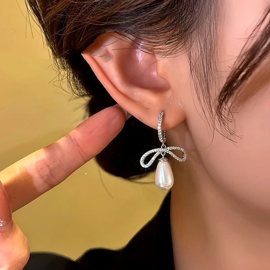 Model showcasing the dangle and style of the 14K Gold-Plated Diamond Bow Bead Earrings