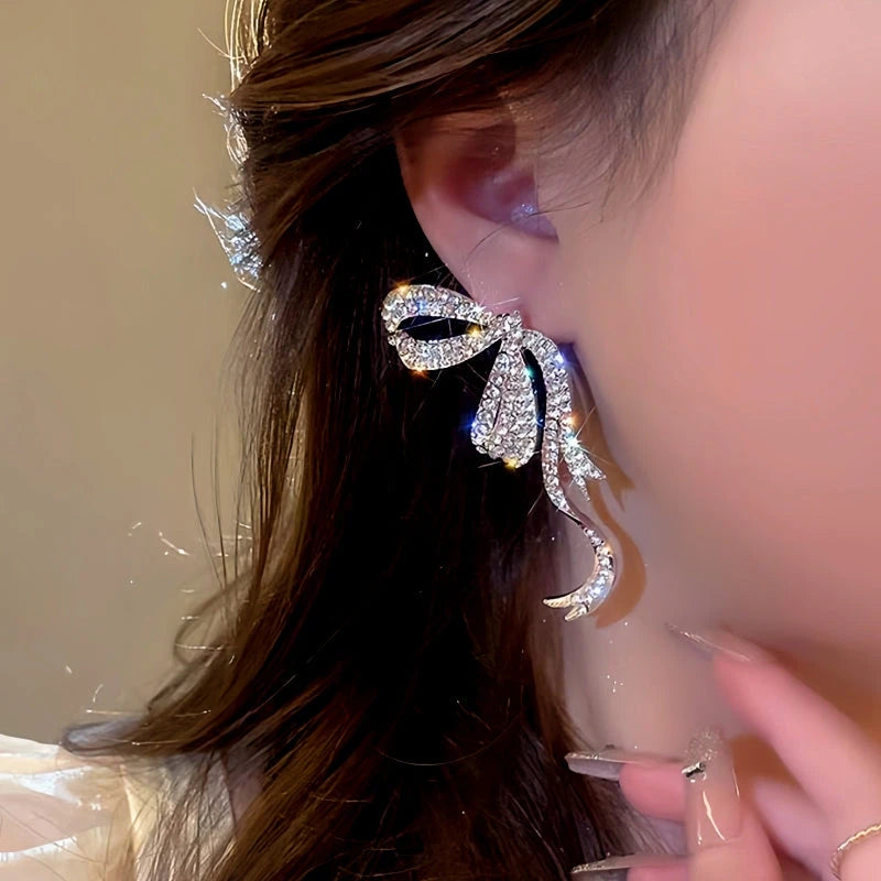 Model showcasing the dangle and style of the 14K Gold-Plated Diamond Bow Earrings