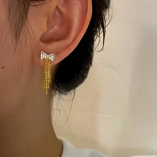 Model showcasing the dangle and style of the 14K Gold-Plated Diamond Bow Earrings