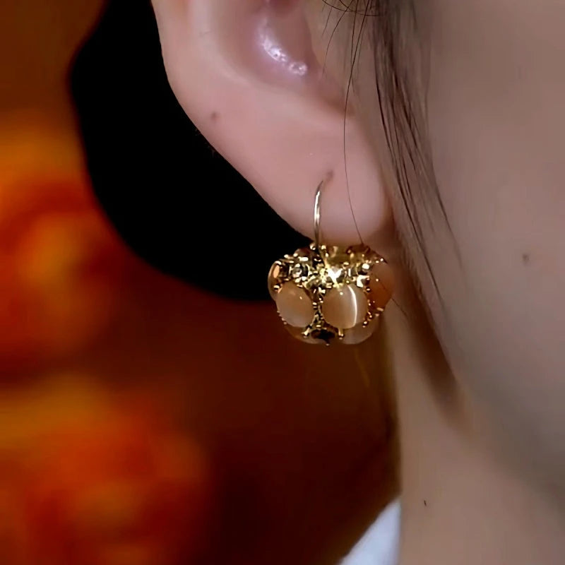 Model showcasing the dangle and style of the 14K Gold-Plated Diamond Brown Cat's Eye Basket Earrings