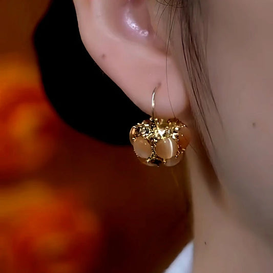 Model showcasing the dangle and style of the 14K Gold-Plated Diamond Brown Cat's Eye Basket Earrings