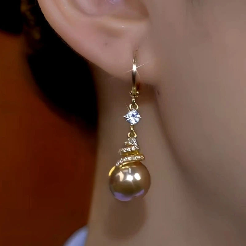 Model showcasing the dangle and style of the 14K Gold-Plated Diamond Brown Pearl Earrings