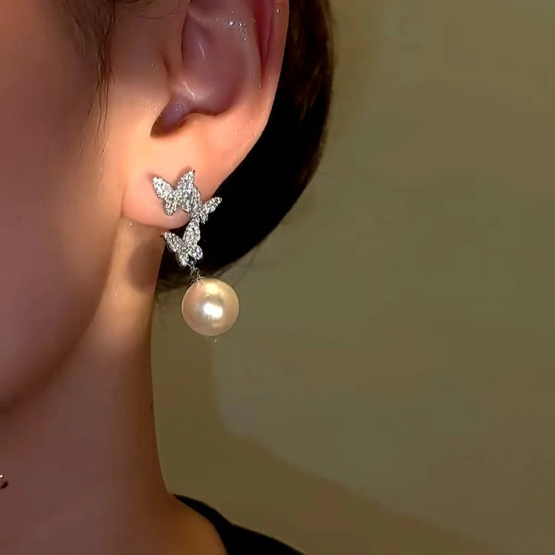 Model showcasing the dangle and style of the 14K Gold-Plated Diamond Butterfly Pearl Earrings