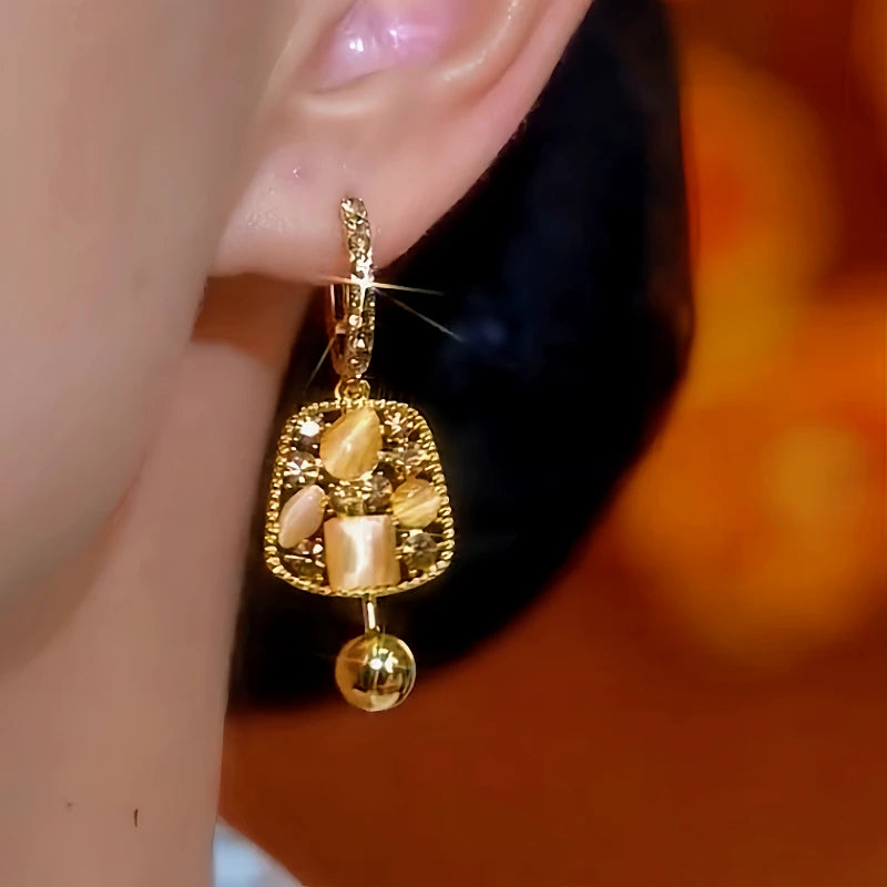 Model showcasing the dangle and style of the 14K Gold-Plated Diamond Cat's Eye Geometric Tassel Earrings